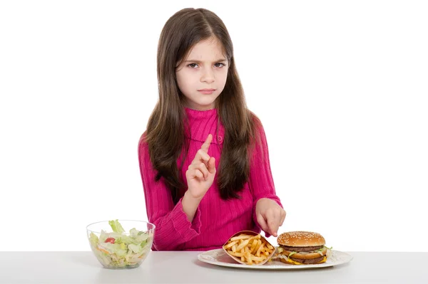 Маленькая девочка со здоровой и нездоровой пищей — стоковое фото