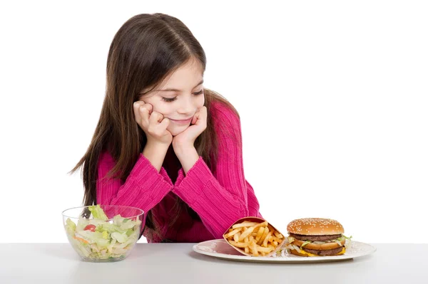 Kleines Mädchen mit gesundem und ungesundem Essen — Stockfoto