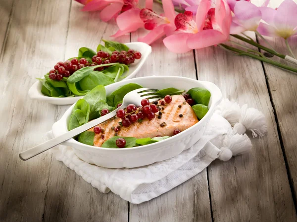 Жареный лосось с красной смородиной и свежим шпинатом — стоковое фото