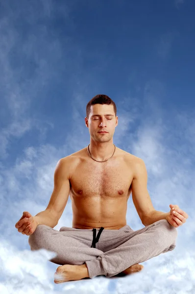 Uomo sulla posizione di yoga contro cielo blu — Foto Stock