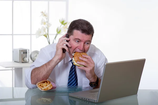 マネージャーの職場で不健康な食べ物を食べる — ストック写真