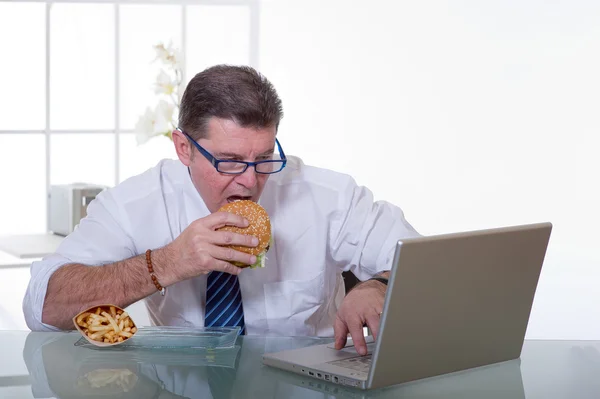 Manager eating unhealthy food at work place — Stock Photo, Image