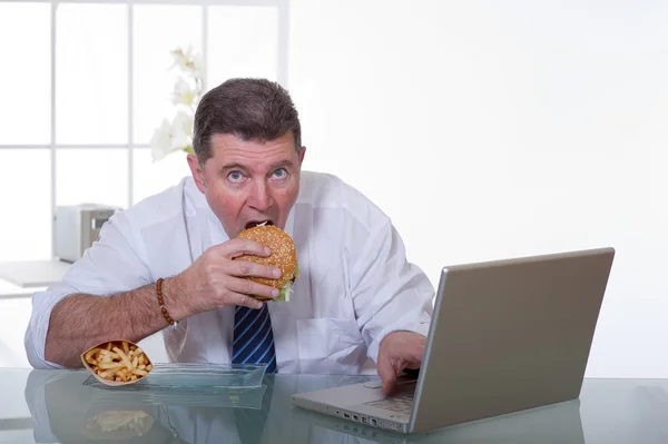 Gestionnaire manger des aliments malsains sur le lieu de travail — Photo