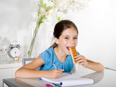 Child eats snack while studying clipart