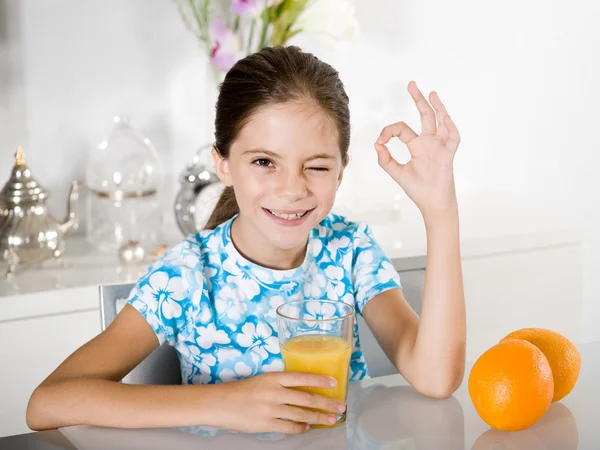 Mała dziewczynka pije sok pomarańczowy — Zdjęcie stockowe