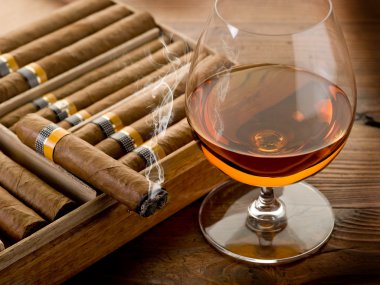 Cuban cigar and cognac on wood background clipart