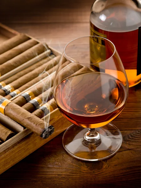 Sigaro cubano e bottiglia di cognac su fondo legno — Foto Stock