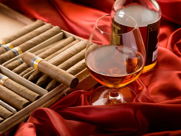 Cubaanse sigaar en drank over rood satijn — Stockfoto