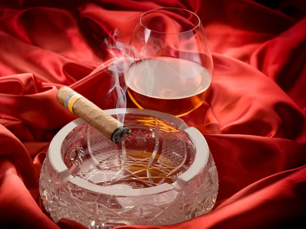 Kubańskie cygaro i i szkło alkohol na czerwono satyna — Zdjęcie stockowe