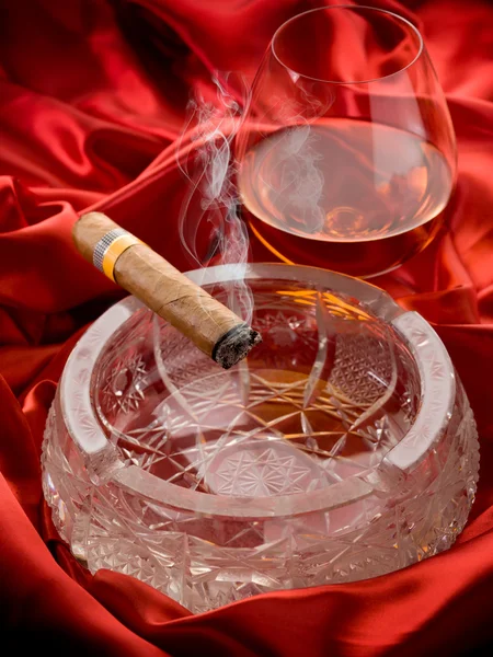 Kubańskie cygaro i i szkło alkohol na czerwono satyna — Zdjęcie stockowe