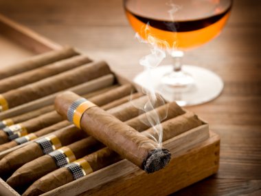 Cuban cigar and glass of liquor on wood background clipart