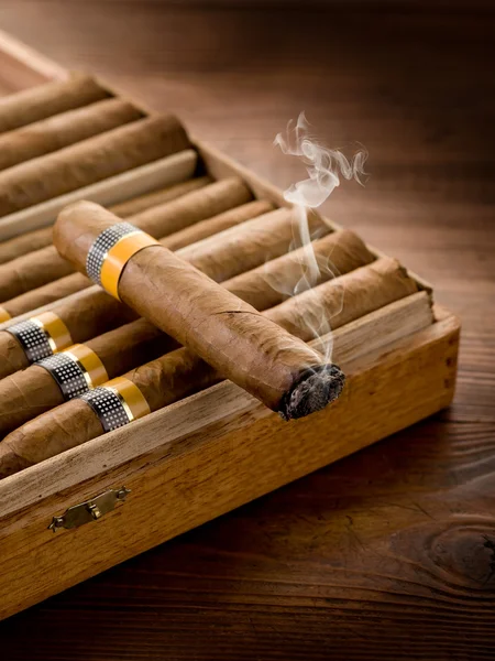 Fumar charuto cubano sobre caixa no fundo de madeira — Fotografia de Stock