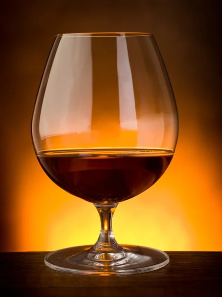 Sklenka alkoholu na dřevěný stůl — Stock fotografie