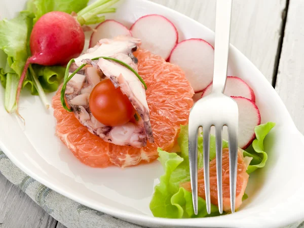 Карпаччо из осьминога над ломтиком грейпфрута с редиской и салатом — стоковое фото