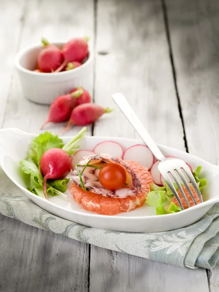 Карпаччо из осьминога над ломтиком грейпфрута с редиской и салатом — стоковое фото