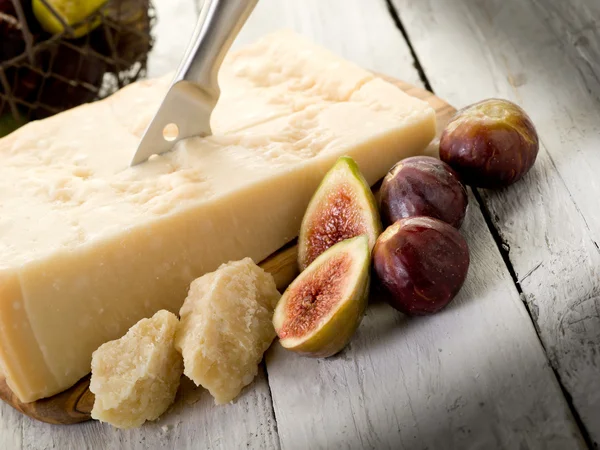Parmesan cheese over cutting board and figs — Stock Photo, Image