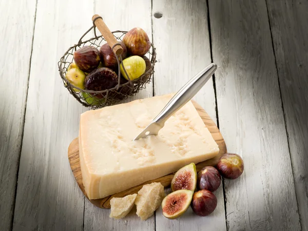 Parmesan cheese over cutting board and figs — Stock Photo, Image