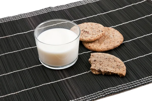 Ein paar Kekse auf einem schwarzen Backhander mit einem Glas Milch — Stockfoto