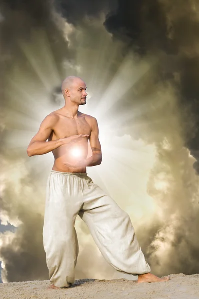 Mann übt Tai, der einen Energieball mit dramatischen Wolken hält — Stockfoto