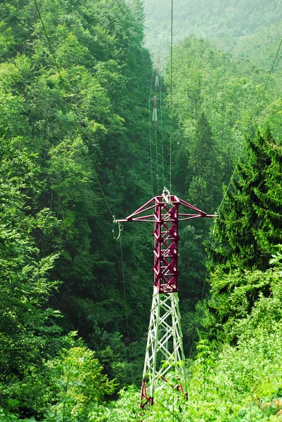 Pólos elétricos de alta tensão através das montanhas — Fotografia de Stock