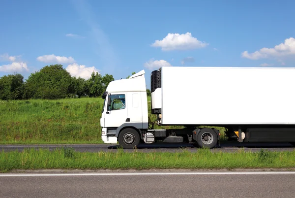 Lange vrachtwagen met witte truck en trailer op snelweg tegen blauwe hemel. — Stockfoto