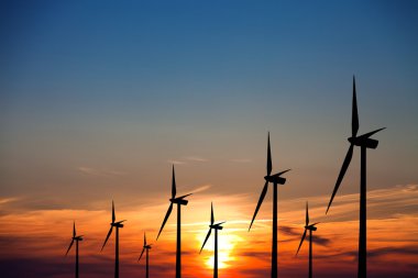 Wind turbines at sunset clipart