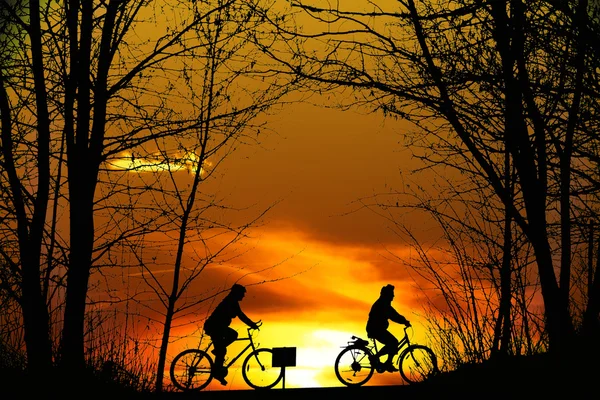 日落时两山骑自行车的人剪影 — 图库照片