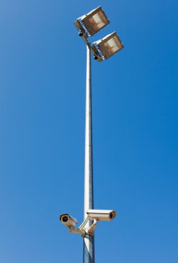 Surveillance camera on light pole in parking clipart