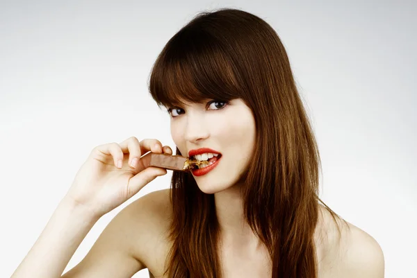 Mulher sexy comendo uma barra de chocolate - estúdio tiro — Fotografia de Stock