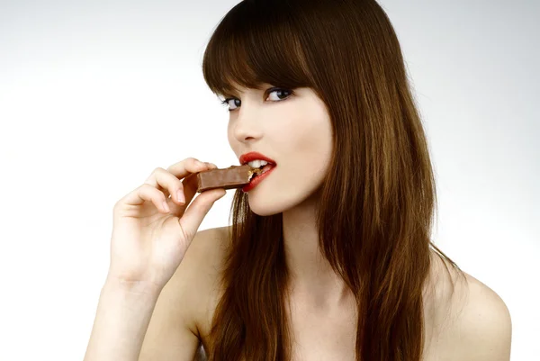 Mujer sexy comiendo una barra de chocolate - filmado en estudio Imagen De Stock
