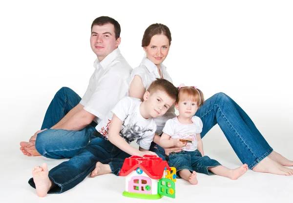 Família feliz perto de uma pequena casa de brinquedo — Fotografia de Stock