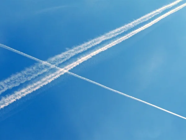 青い空、抽象的な環境上のいくつかの白い飛行機パス. — ストック写真