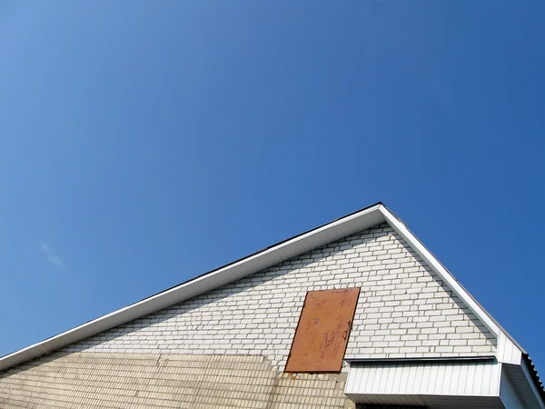 Trojúhelník střechy z bílých cihel na modré obloze. — Stock fotografie