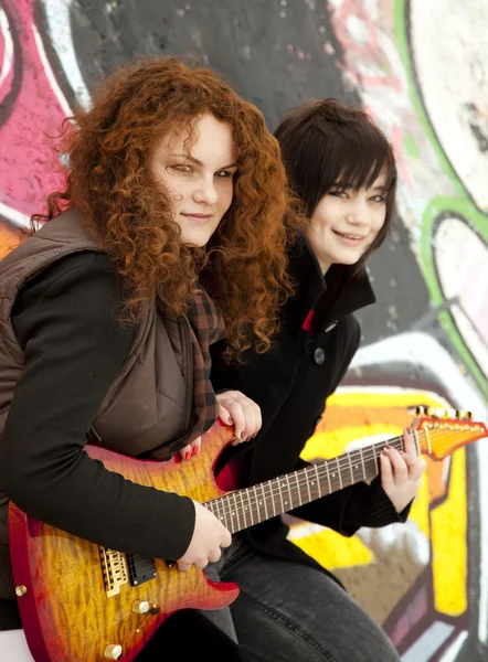 Две стильные девушки-подростки с гитарой на фоне граффити . — стоковое фото