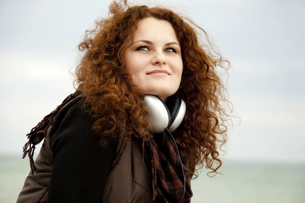Curly red-haired girl with headphones. — Stock Photo, Image