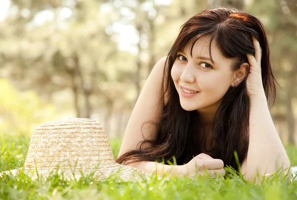 Krásná brunetka s kloboukem v parku. — Stock fotografie