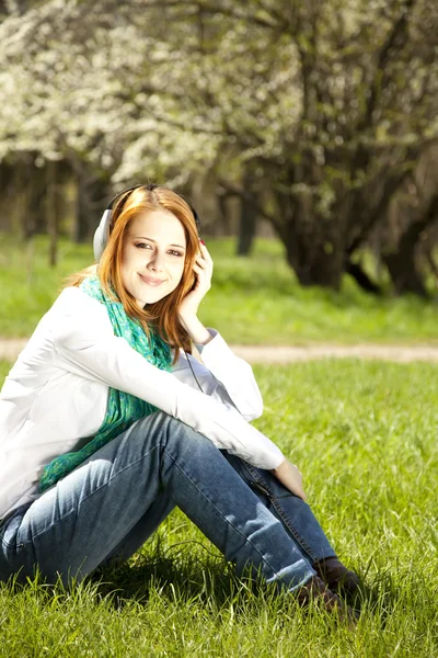 공원에서 헤드폰으로 빨강 머리 소녀. — 스톡 사진