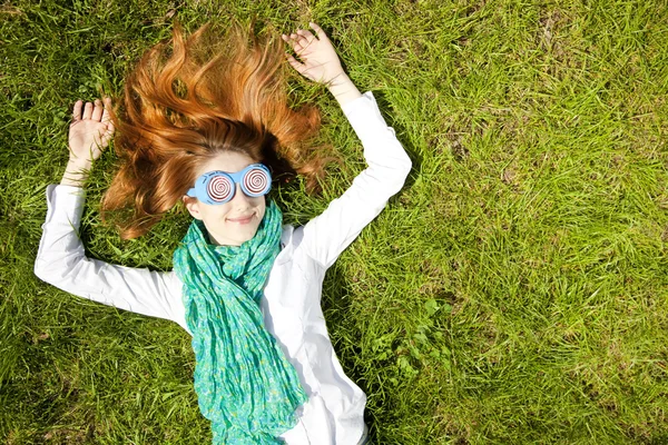 Flicka ligger på grönt gräs i parken. — Stockfoto