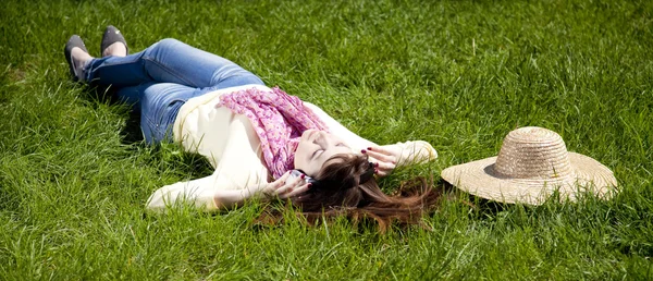 耳机的黑发女孩躺在公园. — 图库照片