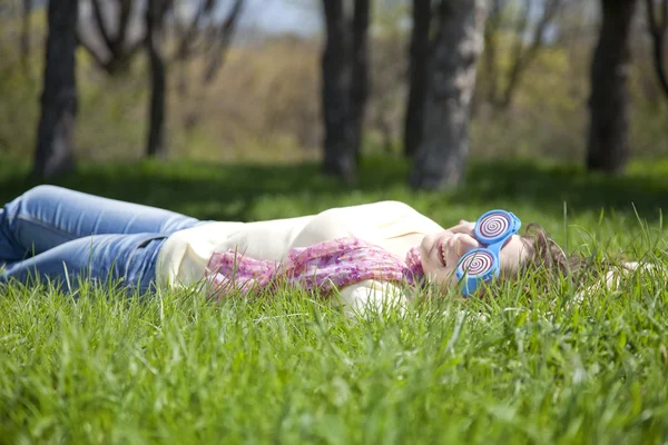 滑稽眼镜的黑发女孩躺在草地上. — 图库照片