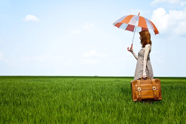 Redhead enchantress with umbrella and suitcase at spring wheat f — Stock Photo, Image