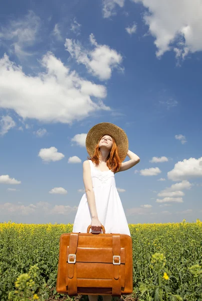 Encantadora pelirroja con maleta en campo de colza de primavera . — Foto de Stock