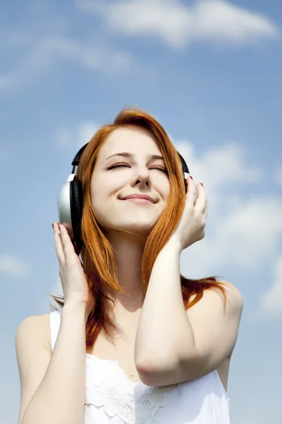 Redhead girl with headphone at sky background. — Stock Photo, Image