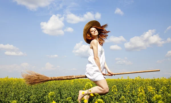 红发女巫的扫帚在飞过春油菜田. — 图库照片