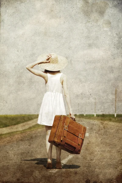 Lonely girl with suitcase at country road. Royalty Free Stock Photos