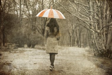 Lonely girl walking at alley in the park in rainy day. clipart