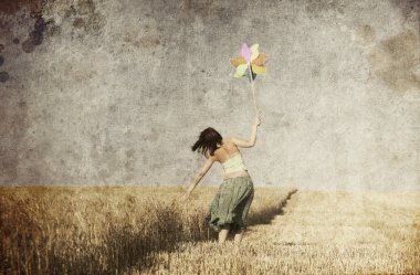 Girl with wind turbine at wheat field. Photo in old color image clipart