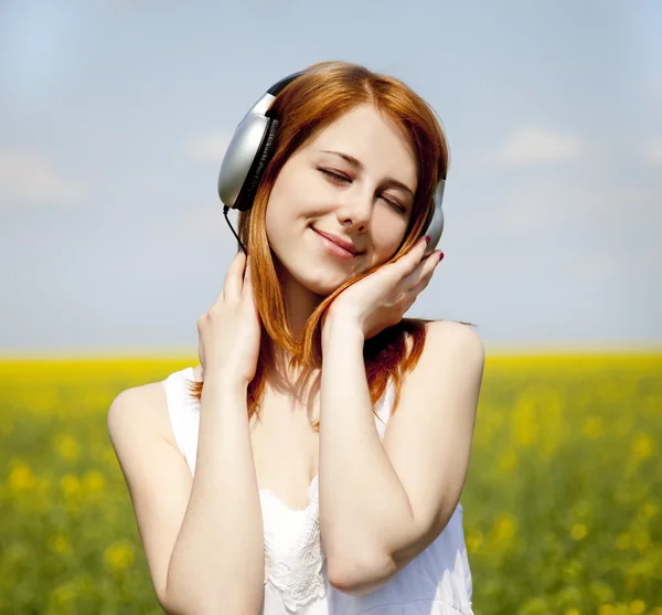 Girl with headphone at rapeseed field. — Stock Photo, Image