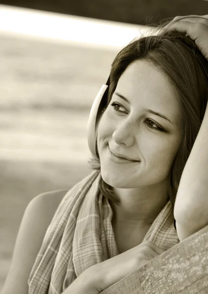 Retrato de menina no fone de ouvido perto de madeira na praia. Foto em — Fotografia de Stock