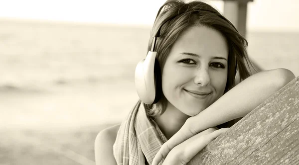 Retrato de niña en auriculares cerca de la madera en la playa. Foto en —  Fotos de Stock